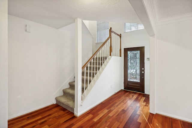 foyer with a textured ceiling, dark hardwood / wood-style floors, and crown molding