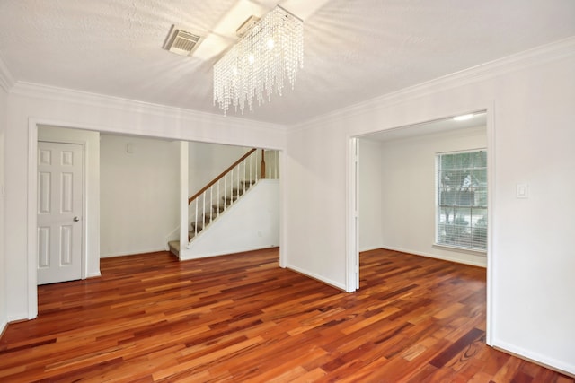 unfurnished room with an inviting chandelier, hardwood / wood-style flooring, ornamental molding, and a textured ceiling