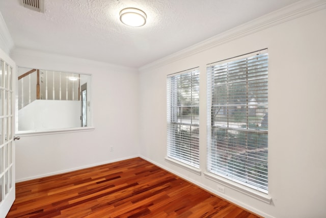 spare room with hardwood / wood-style floors, crown molding, and a textured ceiling