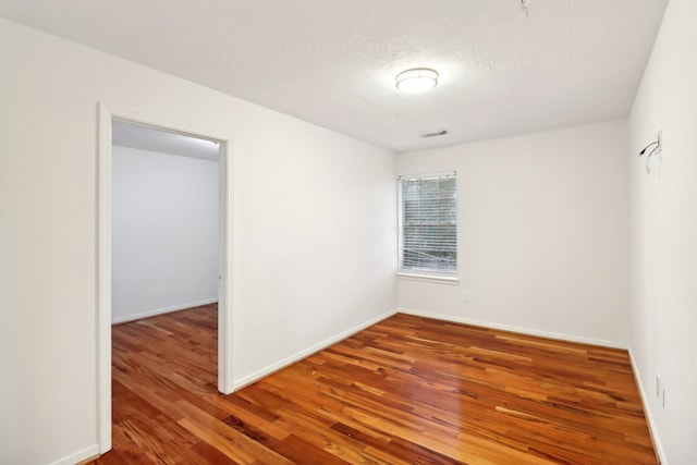 spare room featuring wood-type flooring and a textured ceiling