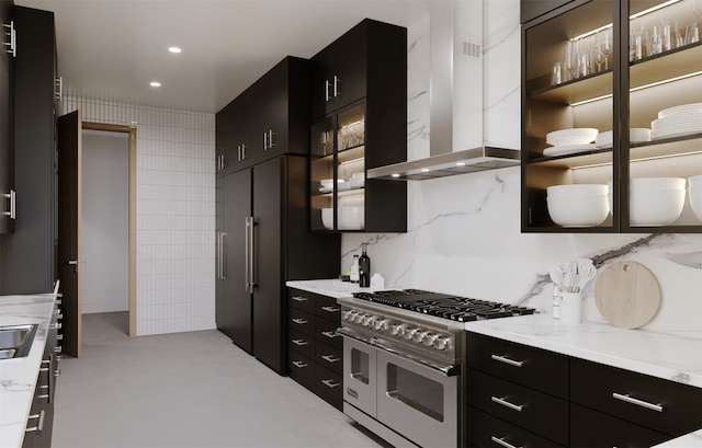 kitchen featuring double oven range, wall chimney range hood, and decorative backsplash