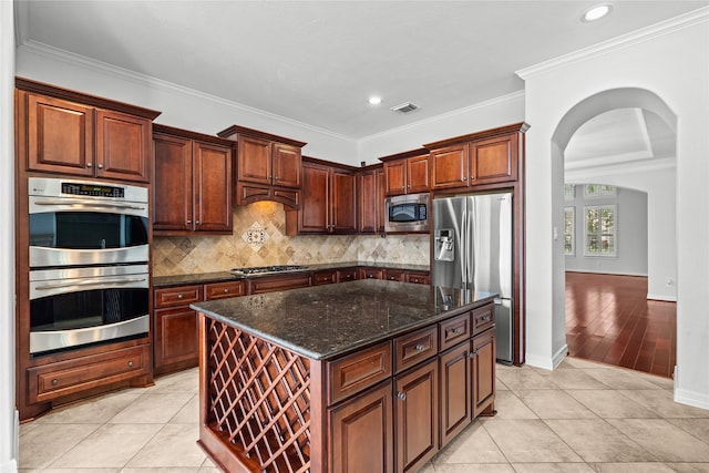 kitchen with ornamental molding, a kitchen island, appliances with stainless steel finishes, and light tile patterned floors