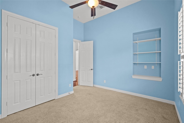 unfurnished bedroom with a closet, light colored carpet, and ceiling fan