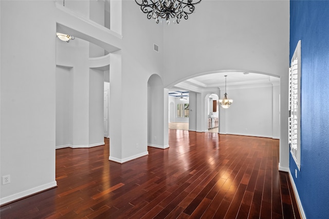 unfurnished living room featuring a towering ceiling, dark hardwood / wood-style floors, and ceiling fan with notable chandelier