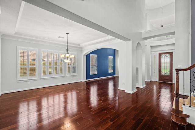 entrance foyer with dark wood-type flooring, ornamental molding, and an inviting chandelier