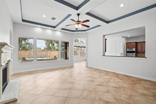 unfurnished living room with ceiling fan, beamed ceiling, light tile patterned flooring, a fireplace, and coffered ceiling