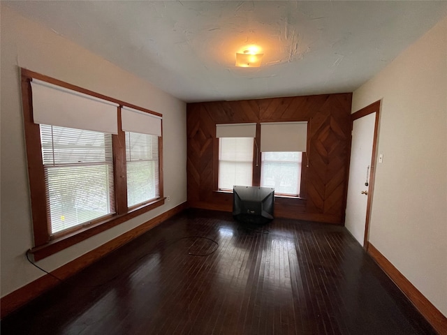 unfurnished room with dark hardwood / wood-style floors and wood walls