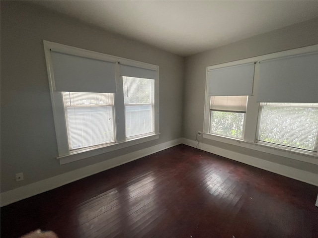 empty room featuring dark wood-type flooring and a wealth of natural light