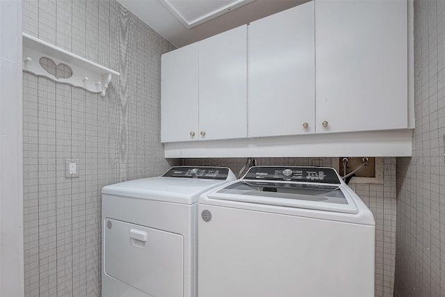 laundry room with tile walls, cabinets, and washing machine and clothes dryer