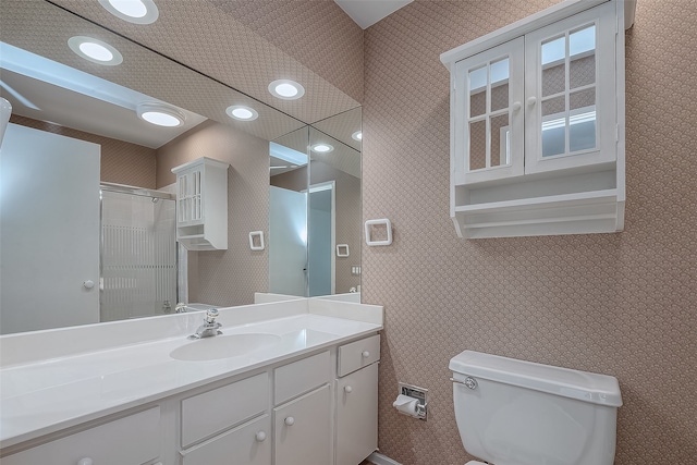 bathroom featuring toilet, vanity, and a shower with shower door