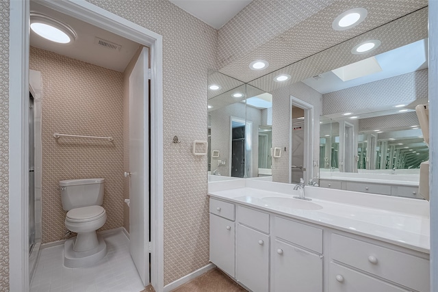 bathroom featuring toilet, tile patterned flooring, vanity, and a skylight