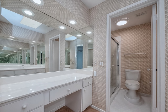 bathroom featuring toilet, vanity, a skylight, and a shower with shower door