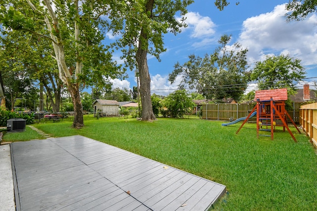 view of yard featuring central AC, a deck, and a playground