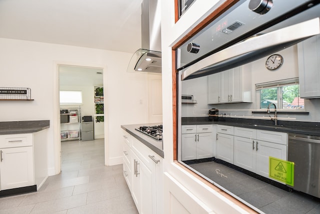 kitchen featuring white cabinetry, stainless steel appliances, wall chimney exhaust hood, and light tile patterned floors