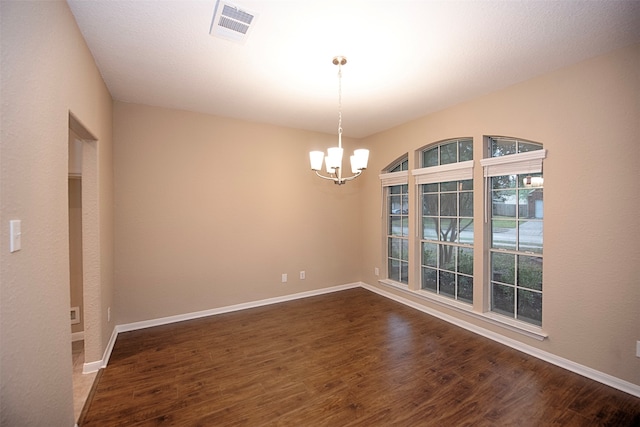 spare room featuring a notable chandelier and dark hardwood / wood-style floors