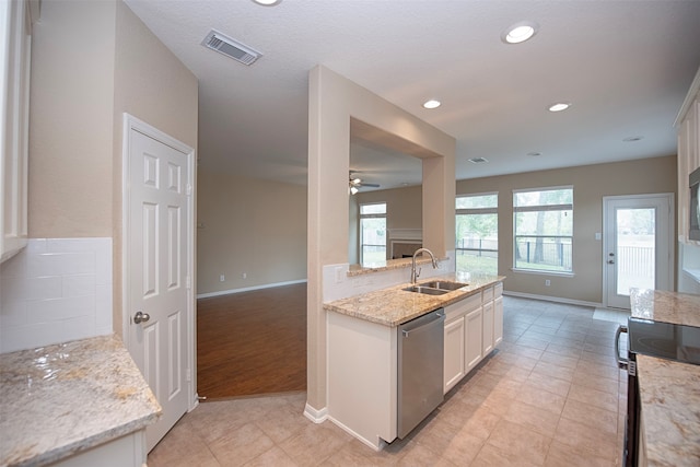 kitchen with black range with electric cooktop, sink, light stone countertops, stainless steel dishwasher, and white cabinetry