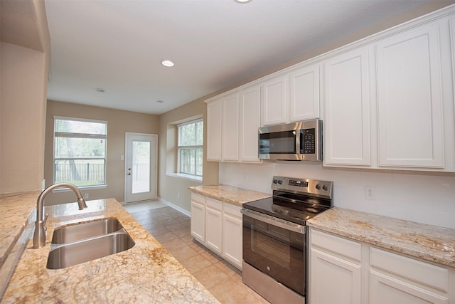 kitchen with white cabinetry, light stone counters, appliances with stainless steel finishes, and sink