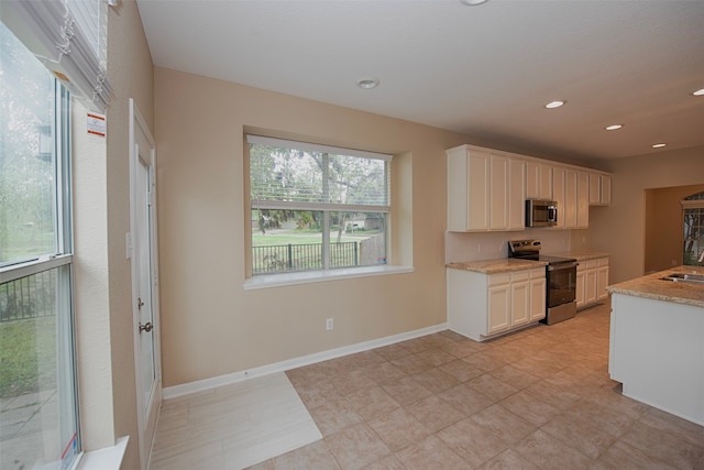 kitchen featuring sink, stainless steel appliances, light tile patterned floors, and white cabinets