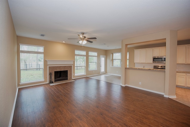 unfurnished living room with dark wood-type flooring, ceiling fan, and a wealth of natural light