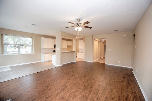 unfurnished living room with ceiling fan, a textured ceiling, and light hardwood / wood-style flooring