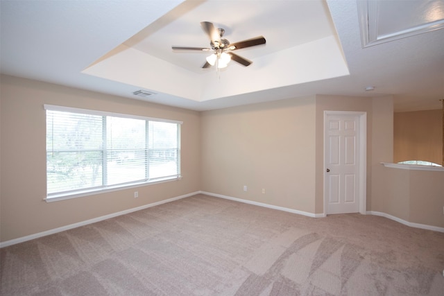 unfurnished room featuring ceiling fan, a raised ceiling, and light colored carpet