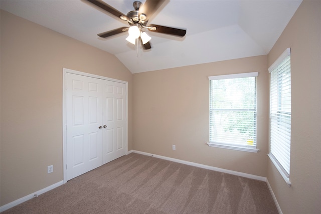 unfurnished bedroom featuring lofted ceiling, light carpet, a closet, and ceiling fan