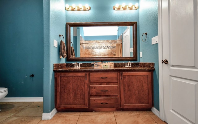 bathroom with toilet, vanity, and tile patterned floors