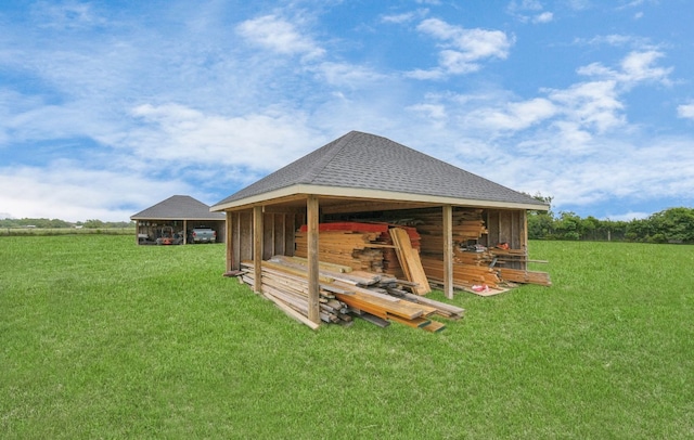 back of property with a rural view, an outdoor structure, and a lawn