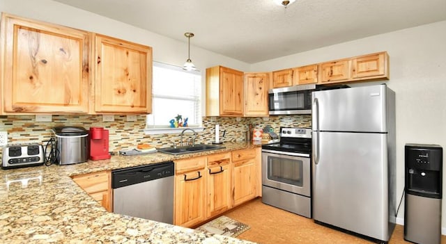 kitchen featuring sink, stainless steel appliances, pendant lighting, decorative backsplash, and light brown cabinets