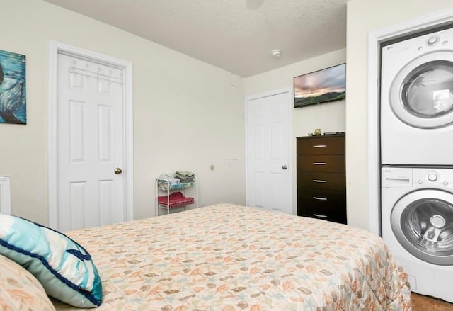 bedroom with stacked washing maching and dryer and a textured ceiling