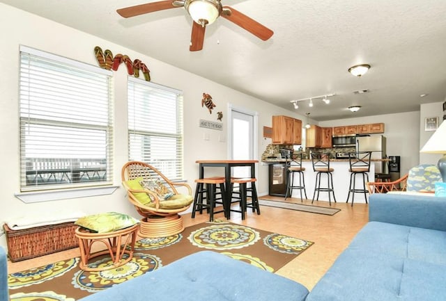 living room featuring ceiling fan and a textured ceiling