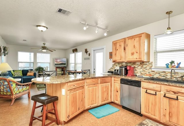 kitchen featuring a kitchen bar, dishwasher, kitchen peninsula, and a textured ceiling