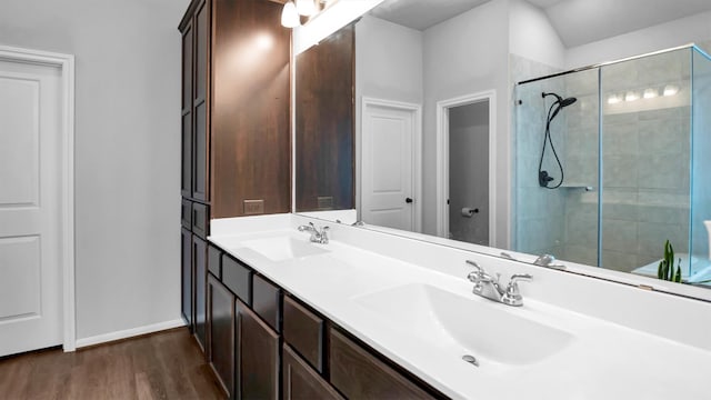 bathroom with vanity, hardwood / wood-style floors, vaulted ceiling, and a shower with shower door