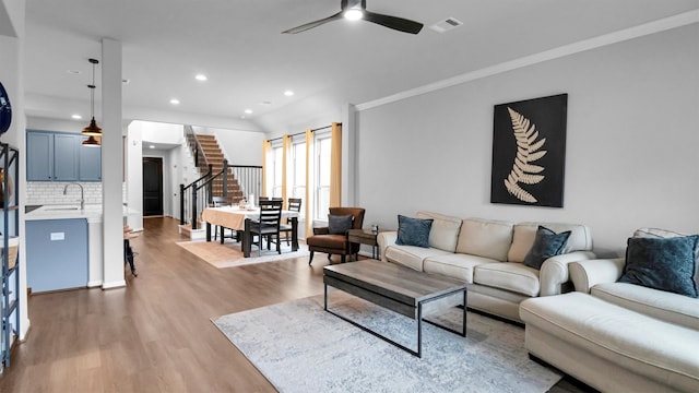 living room featuring sink, ceiling fan, wood-type flooring, and ornamental molding