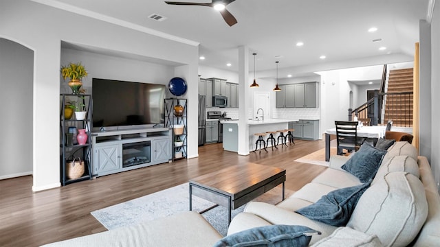 living room with crown molding, ceiling fan, sink, and dark hardwood / wood-style flooring