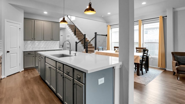 kitchen with sink, an island with sink, pendant lighting, and dark hardwood / wood-style floors