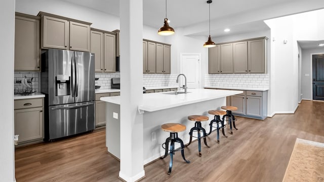 kitchen featuring a kitchen breakfast bar, hanging light fixtures, sink, stainless steel fridge with ice dispenser, and tasteful backsplash