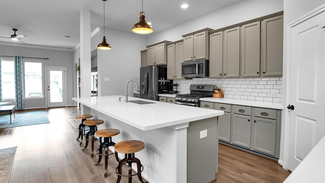 kitchen with decorative backsplash, hanging light fixtures, a breakfast bar, light hardwood / wood-style floors, and stainless steel appliances