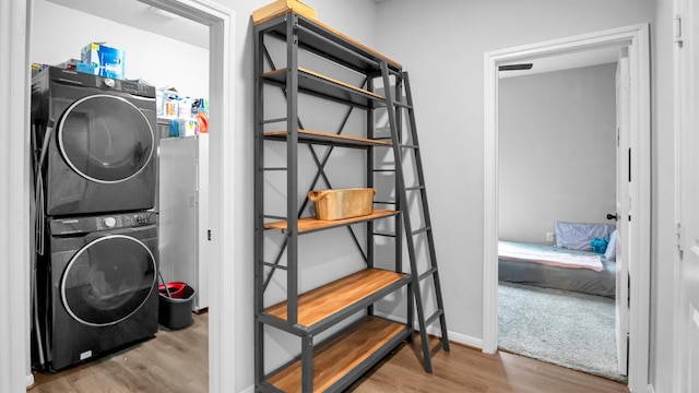 clothes washing area with light hardwood / wood-style floors and stacked washer / drying machine