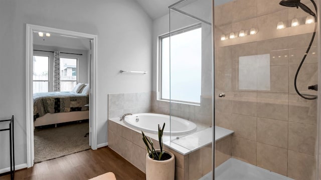 bathroom with shower with separate bathtub, hardwood / wood-style flooring, and vaulted ceiling