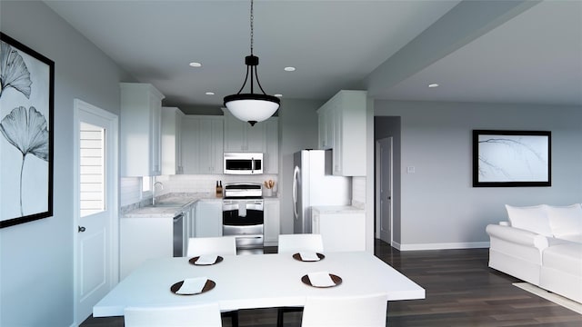 kitchen featuring appliances with stainless steel finishes, dark wood-type flooring, sink, white cabinets, and hanging light fixtures