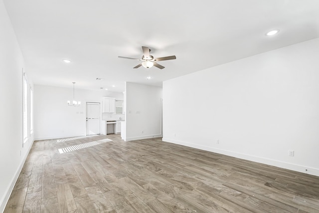 unfurnished living room with ceiling fan with notable chandelier and hardwood / wood-style flooring