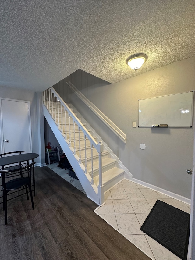 staircase featuring a textured ceiling and hardwood / wood-style flooring