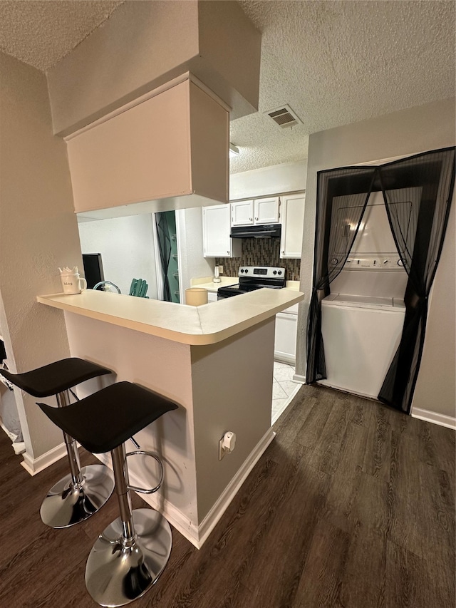 kitchen featuring a kitchen breakfast bar, kitchen peninsula, white cabinets, a textured ceiling, and dark hardwood / wood-style flooring