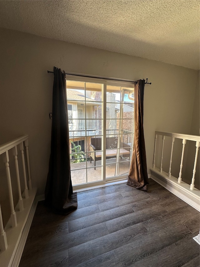 empty room with a textured ceiling and dark hardwood / wood-style flooring