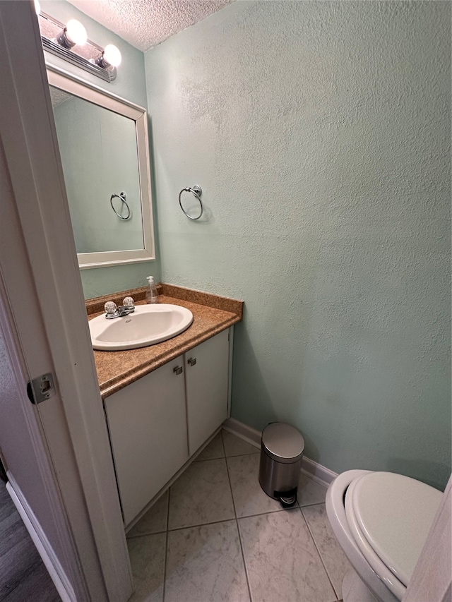 bathroom with vanity, a textured ceiling, toilet, and tile patterned floors