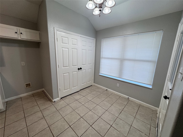 unfurnished bedroom with a chandelier, vaulted ceiling, a closet, and light tile patterned floors