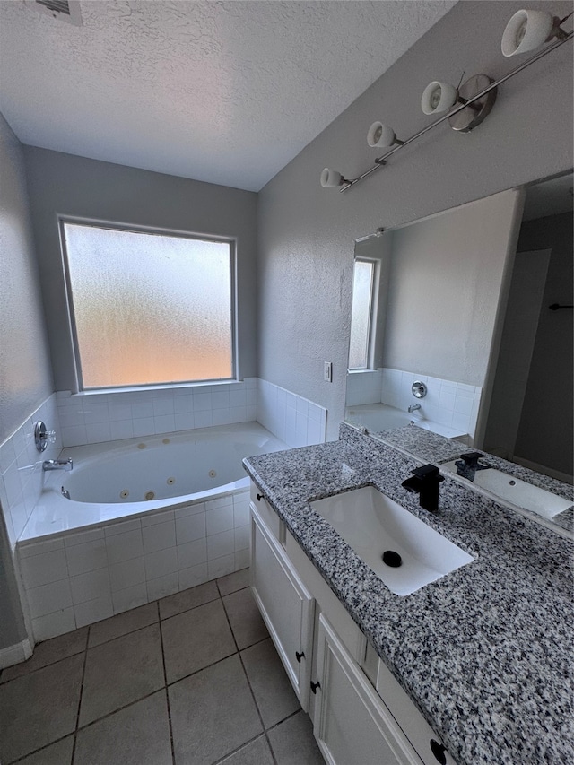 bathroom with vanity, a textured ceiling, a relaxing tiled tub, and tile patterned floors