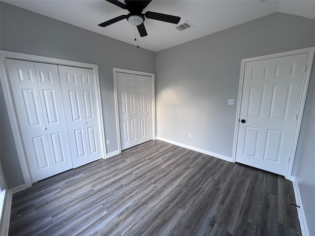 unfurnished bedroom featuring ceiling fan, dark hardwood / wood-style flooring, and two closets