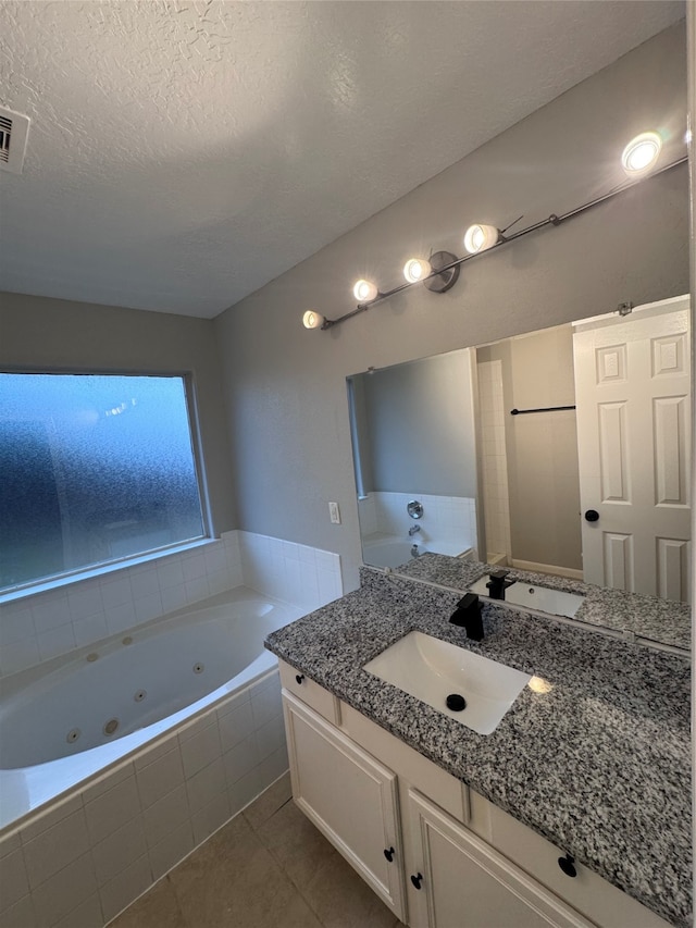 bathroom featuring vanity, a relaxing tiled tub, a textured ceiling, and tile patterned flooring